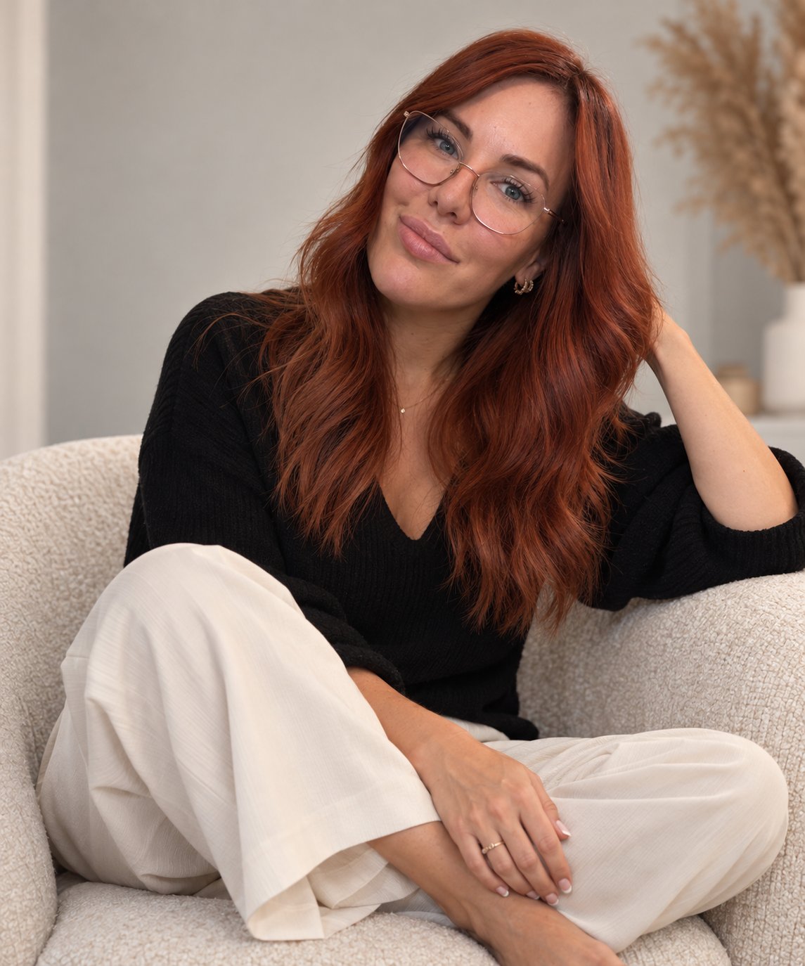 Melanie Straub mit kupferroten Haaren und Brille im hellen Sessel